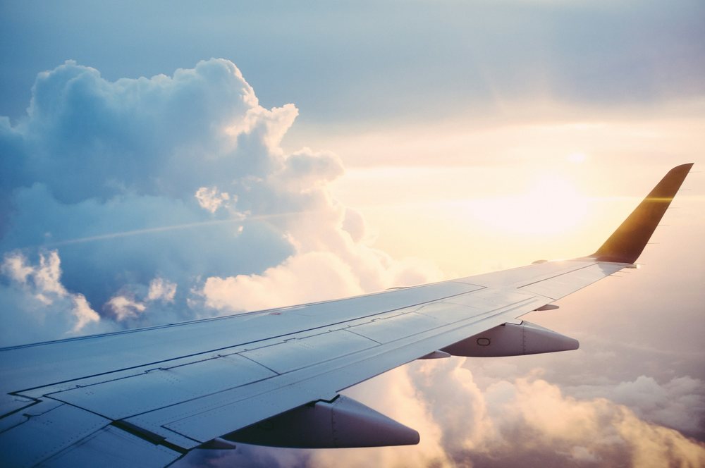 Airplane wing above clouds at sunset